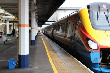 İngiltere 'nin güneyindeki Sheffield, Güney Yorkshire' da bir tren istasyonunda yolcularla birlikte bir platformda bekleyen bir Doğu Midlands treni görüntüsü.