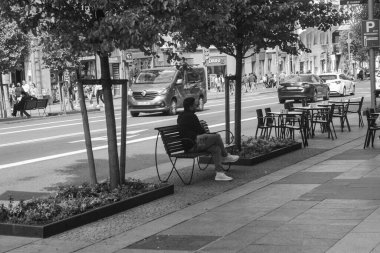 Madrid 'de bir bankta oturan bir insan, geri kalanını gri tonda seyrediyor.