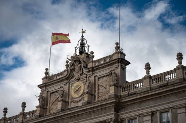 İspanyol bayrağının yakın çekimi ve Madrid 'deki kraliyet sarayının ön cephesindeki saat.
