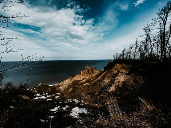 岩石悬崖的自然景观 树木无叶 蓝天白云下积雪融化 — 图库照片