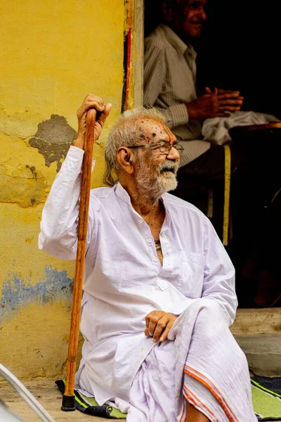 印度Nathdwara 一位身穿白色传统服装的印度老人坐在一面黄色的墙上 — 图库照片