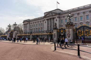 Buckingham Sarayı 'nın açılı bir görüntüsü, turistler ve Birlik bayrağı tam direkte.
