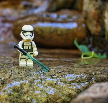 Sudaki kayanın üzerinde elinde kılıçla duran askerin yakın plan fotoğrafı.