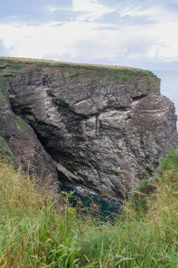 İskoçya ve İngiltere 'nin sakin mavi gökyüzü altında, İskoçya kıyısındaki kayalık bir uçurumun dikey görüntüsü