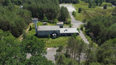 Yeşil doğayla çevrili eski terk edilmiş bir binanın havadan görüntüsü.
