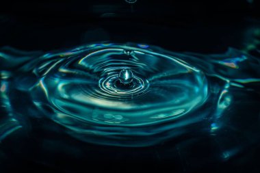 Siyah arkaplanda izole edilmiş bir su damlasının yakın çekimi.