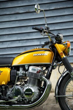 Açık havada park edilmiş sarı bir Honda CB750 bisikletin dikey görüntüsü.
