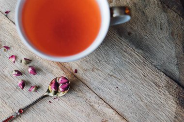 Yüksek açılı pembe, kırmızı rooibos çayı kaşıkla gül dolu ahşap fıçıda.