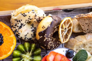 Tabakta çeşitli meyveler, peynir, ekmek ve tatlılardan oluşan yakın plan.