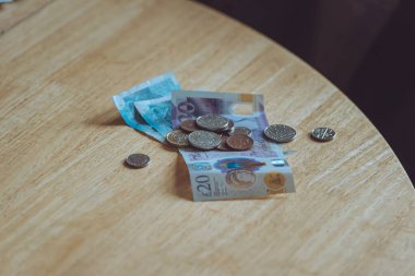 Tahta bir masanın üzerinde birkaç banknot ve bozuk para. Ekonomik kriz, yoksulluk, parasızlık kavramı.