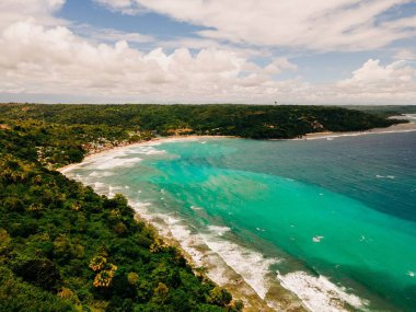 Bulutlu gökyüzünün altında yeşilliklerle kaplı güzel bir uçurum kıyısı.