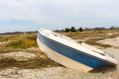 Sahilde arkasında gökyüzü olan terk edilmiş küçük bir tekne.
