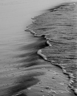 Kumlu bir sahilde dalgaların gri pulu