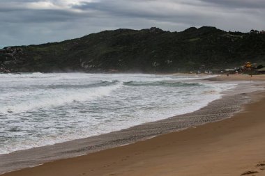 Bulutlu bir deniz manzarası ve uzak bir orman dağı