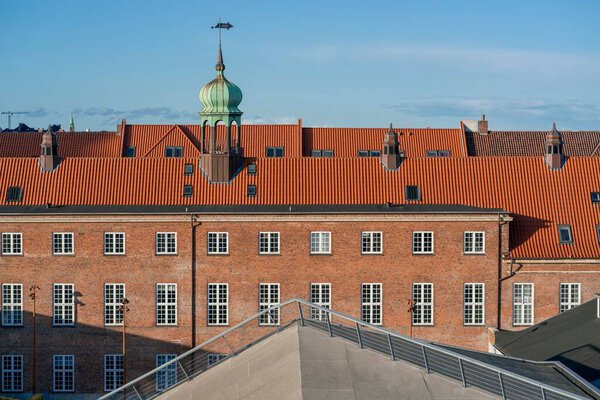 A building in Copenhagen with a red rooftop and brick wall on a sunny day