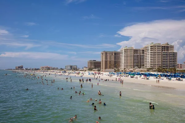 Clearwater plajının, suda yüzen ve Florida sahillerinde dinlenen insanların resimli görüntüsü.