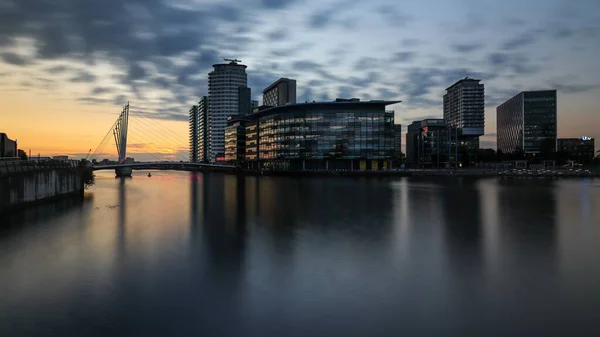 イギリス マンチェスター市のSalford Quays川の上の近代的な建物や橋の夕景 — ストック写真