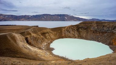 Gün boyunca dağlarla çevrili bir gölün büyüleyici görüntüsü.
