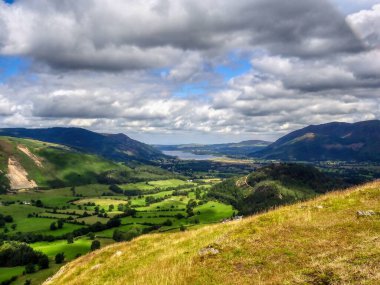 Kırsal kesimdeki bulutlu gökyüzü arka planında yeşil dağlık bir arazinin güzel manzarası.