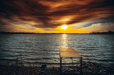 Gün batımının güzel manzarası sakin bir denizin üzerinde - rıhtımlı bir sahilden manzara