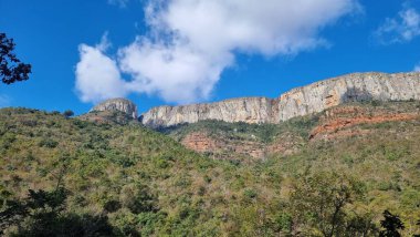 Alçak açılı bir kayalık dağ manzarası ve tabanında bitki örtüsü.