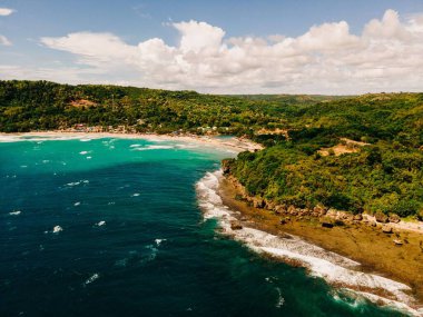 Bulutlu gökyüzünün altında yeşilliklerle kaplı güzel bir uçurum kıyısı.