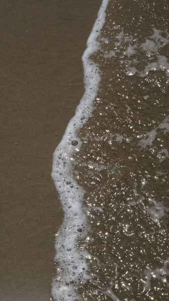 Vertikální Záběr Vln Mořské Pěny Písečné Pláži — Stock fotografie