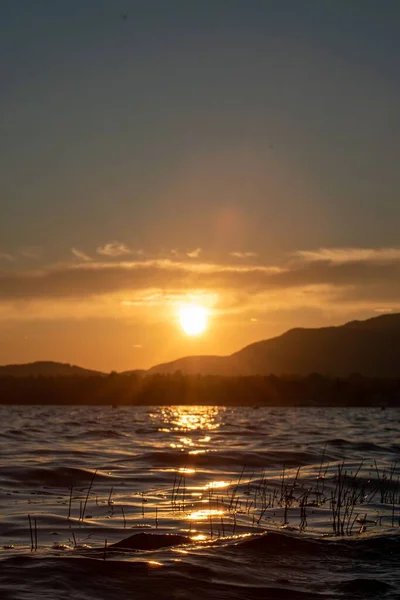 Eine Vertikale Aufnahme Eines Sonnenuntergangs Über Einem Ruhigen Meerwasser Und — Stockfoto