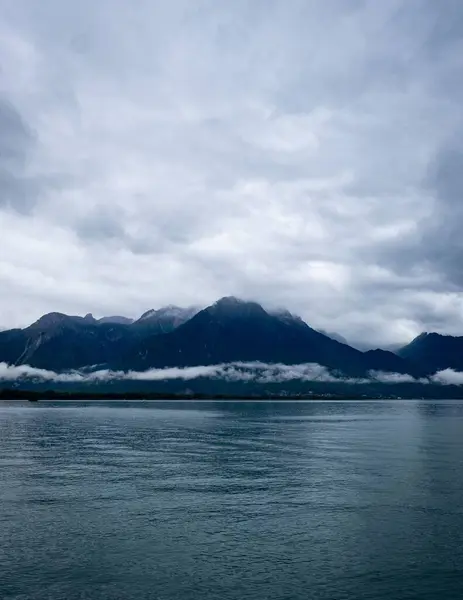 一片平静的大海 群山耸立 地平线上乌云密布 — 图库照片