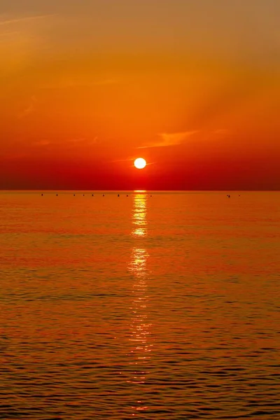 Pionowe Ujęcie Pomarańczowego Czerwonego Zachodu Słońca Nad Morzem Wodą Odbijającą — Zdjęcie stockowe