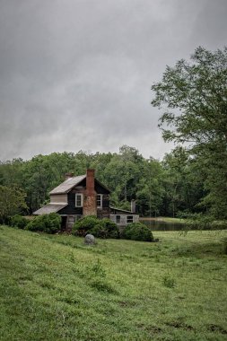 Bulutlu bir gökyüzü ve çayırda tek bir ev