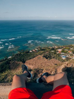 Güneşli bir günde Hawaii, Honolulu 'da Diamond Head' in tepesinde oturan bir erkek turistin dikey görüntüsü.