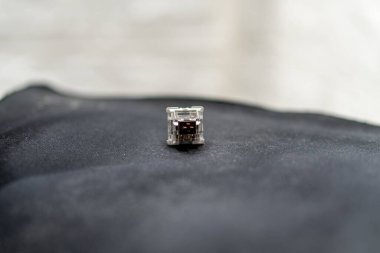 Karanlık bir kumaş üzerinde izole edilmiş mekanik bir klavye anahtarının yakın çekimi