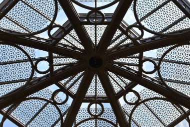 Arka planda mavi gökyüzü olan simetrik bir metal ve cam tavan..