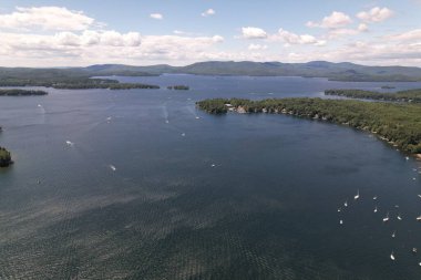 Newfound Gölü 'nün havadan görünüşü, NH' de su üzerinde tekneler, ağaçlar ve arka planda bulutlar.