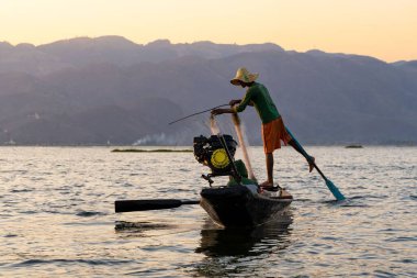 Inle Gölü, Myanmar 'da gün batımında kürek çeken bir balıkçı.