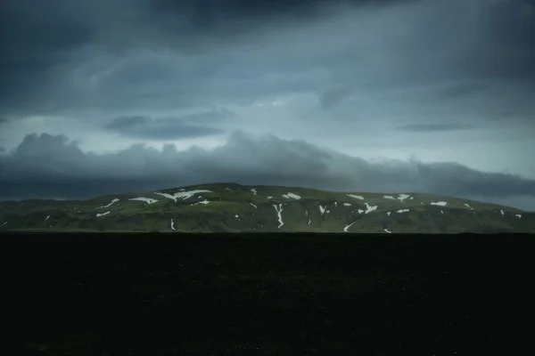 Grön Kulle Med Snö Bakgrunden Ett Fält Den Dystra Himlen — Stockfoto