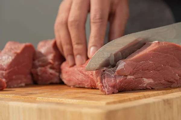 板の上でナイフを使って肉を切った男の姿を間近で見ることができる — ストック写真