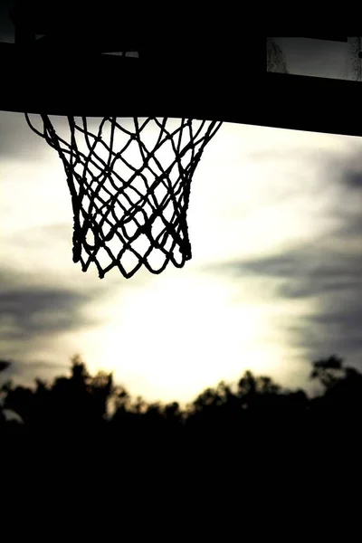 以阳光为背景的单色篮球圈和网状传送器的轮廓 — 图库照片