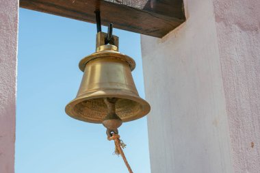 Açık havada asılı duran bronz bir çanın yakın çekimi.