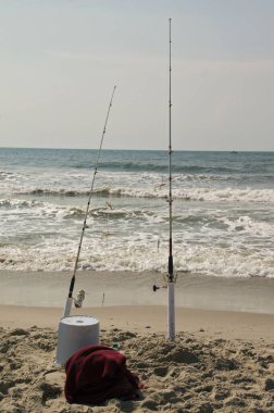 Balık oltaları ve kumlu sahilde bir kova