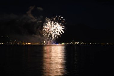 Gece gökyüzünde parlayan ve Tegernsee, Bavyera, Almanya 'da suyu yansıtan güzel altın havai fişekler.