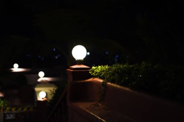 Karanlık bir bahçede yanan yuvarlak lambalar