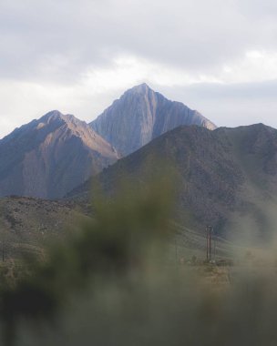 Bulutlu gökyüzünün altındaki dağların dikey görüntüsü