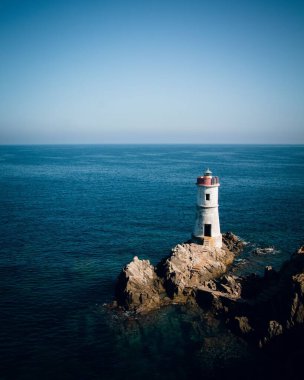 Deniz kıyısındaki bir deniz fenerinin dikey yüksek açılı görüntüsü