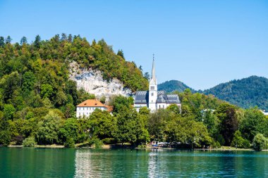 Slovenya 'da orman ve kilise binası olan bir tepenin yanındaki Bled Gölü