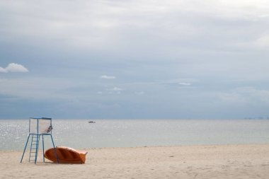 Açık bir günde güneşli bir sahil. Kumsal gözetleme kulesi ve ahşap bir tekne.