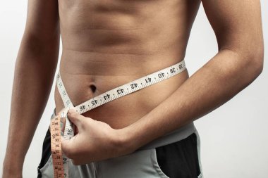 Bel ölçüsünü beyaz arka planda izole edilmiş bant ölçüsüyle ölçen fitness modeli