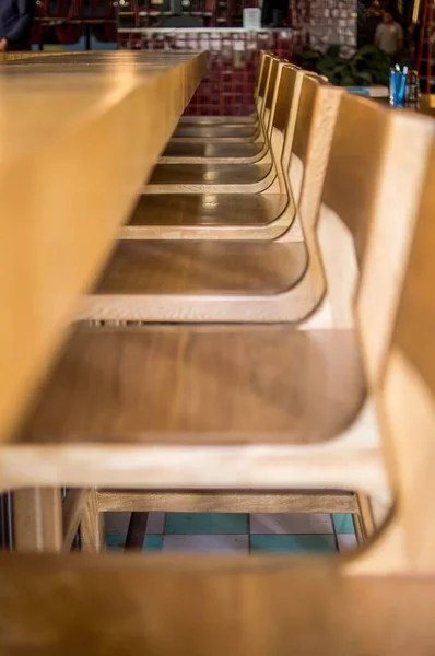 Closeup Row Wooden Bar Stools Thick Seats Facing Counter — Stock Photo, Image