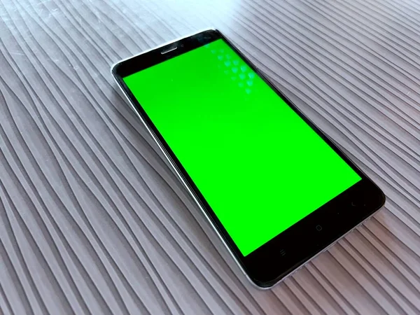 一种没有品牌的智能手机 桌上有空白的绿色屏幕 — 图库照片